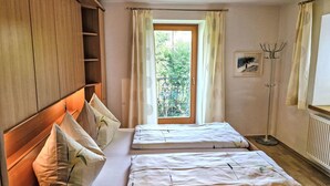 A room with two beds, wooden wardrobe, a window with curtains, a radiator, and a coat rack. - Lueg ins Land by Interhome (Reith bei Seefeld)