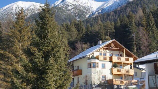 A chalet-style building with a balcony, surrounded by snow-covered mountains and evergreen trees. - Lueg ins Land by Interhome (Reith bei Seefeld)