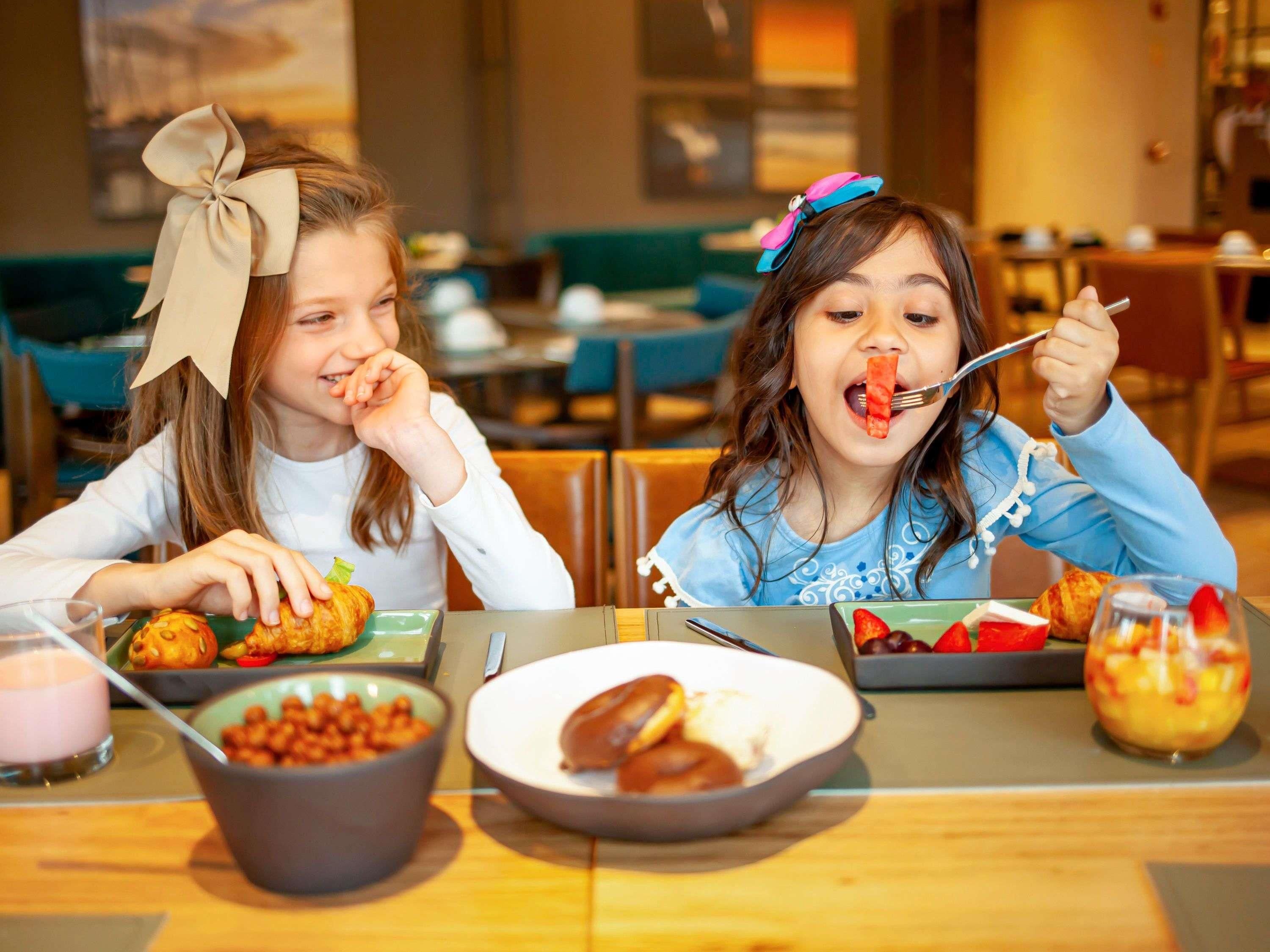 Dos personas sentadas a una mesa con diferentes alimentos y un vaso de una bebida rosada.