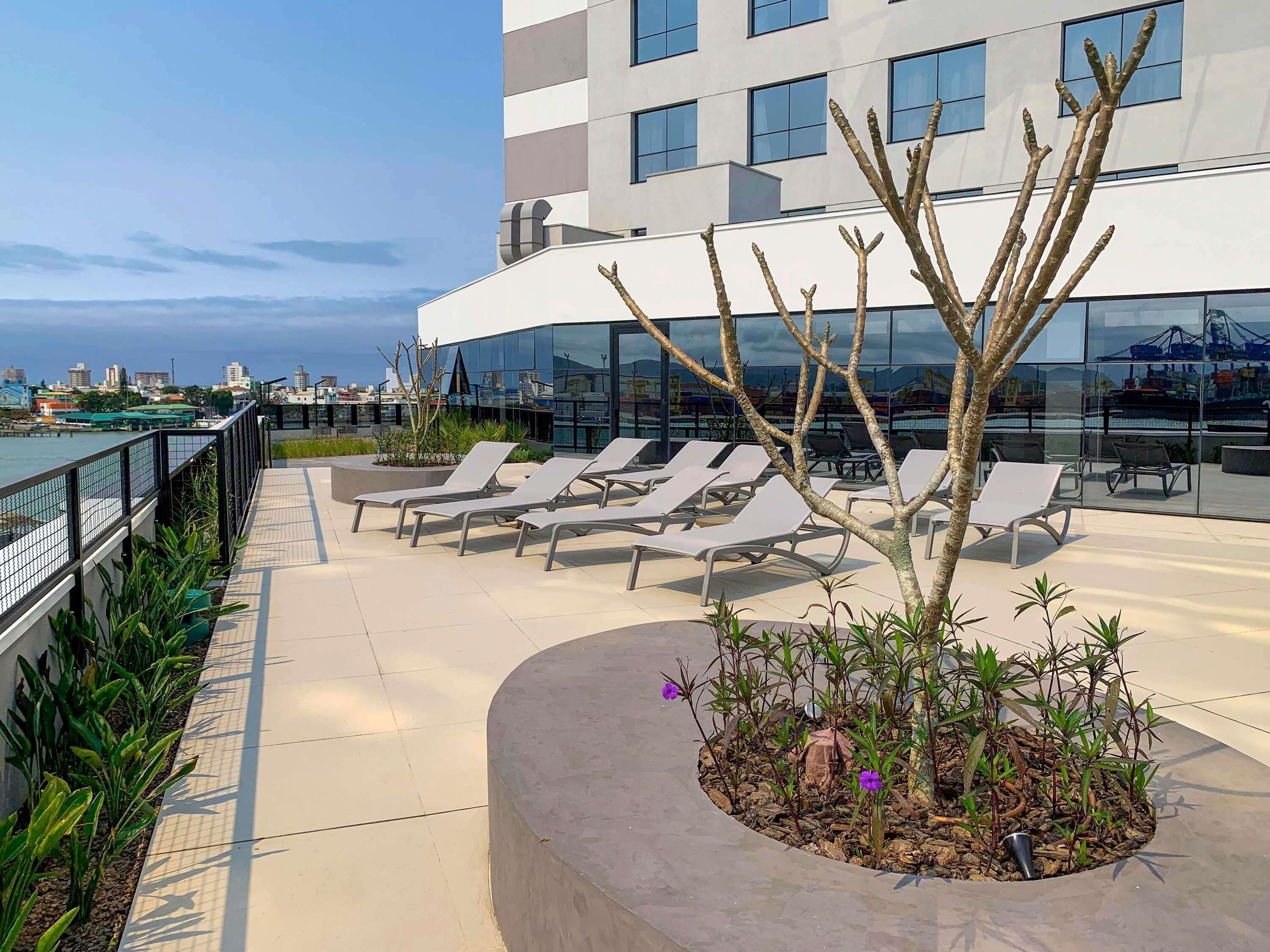 A rooftop terrace with lounge chairs, a small garden, and a view of the city skyline.