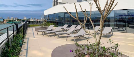 A rooftop terrace with lounge chairs, a small garden, and a view of the city skyline.