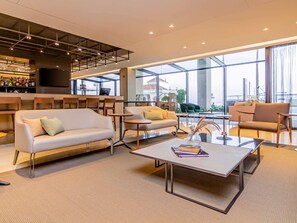 Un espace de détente moderne avec des canapés, des tables et un bar.