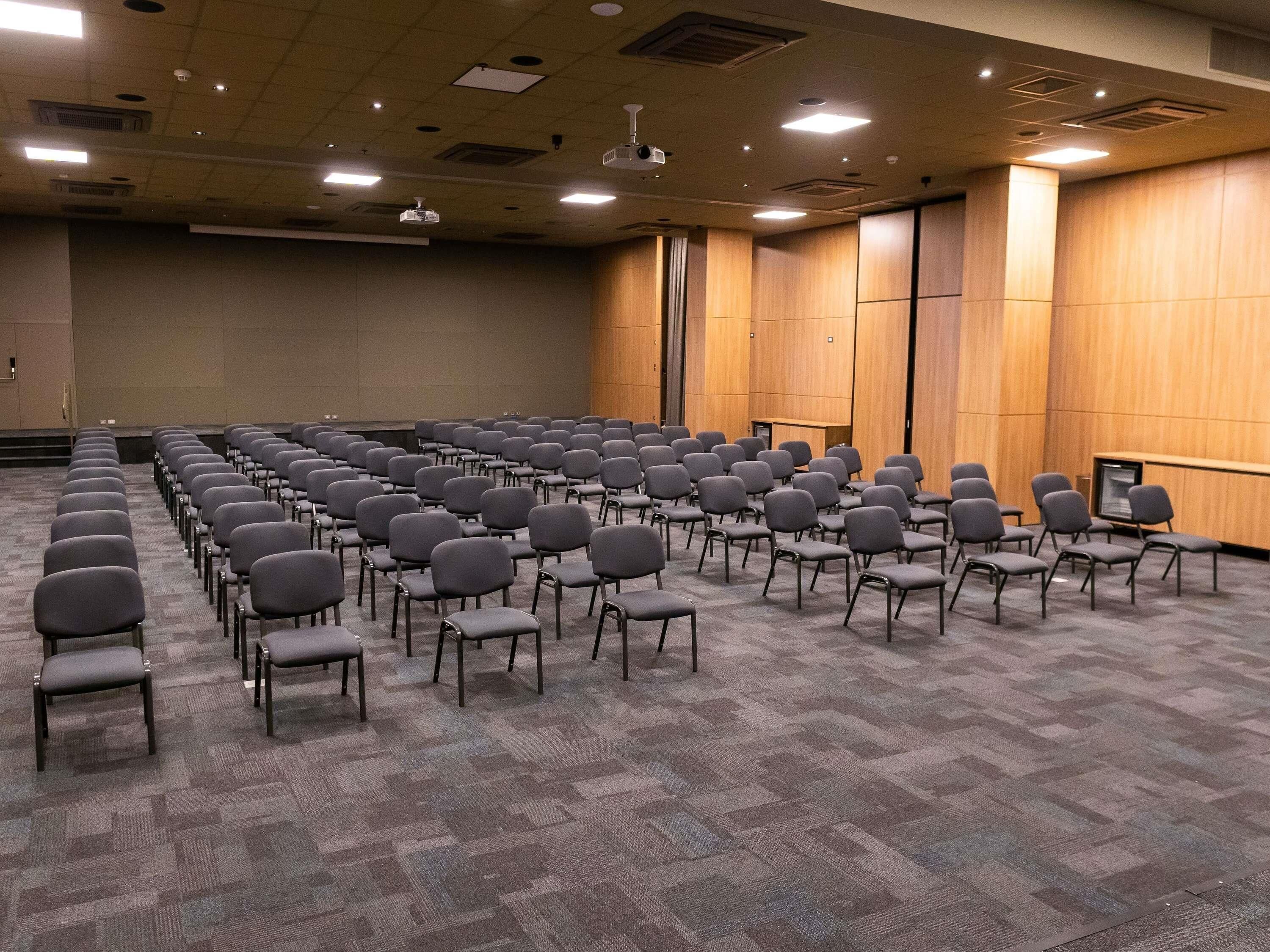 Konferenssihuone, jossa on riveissä tuoleja ja lattialla on matto.