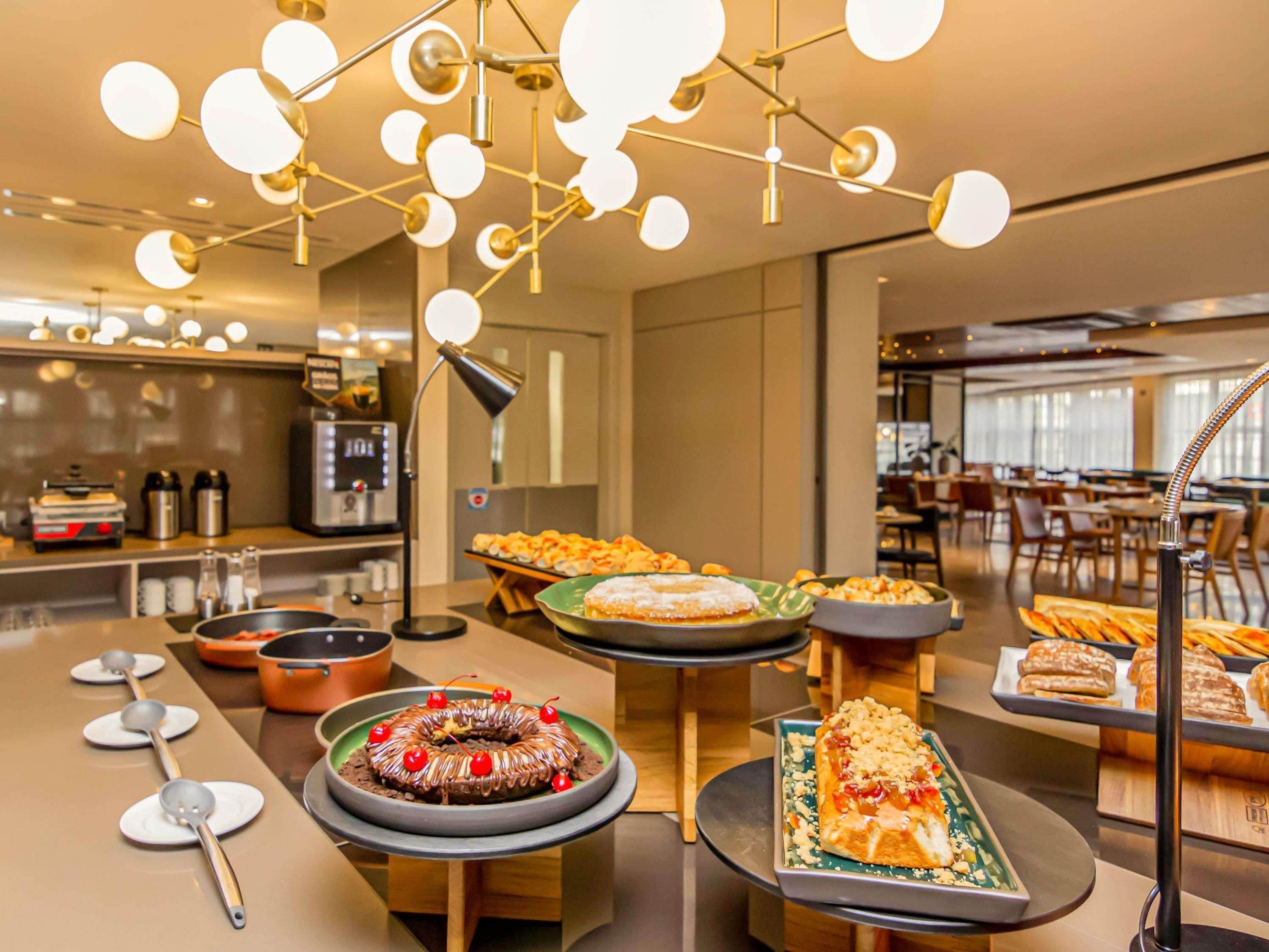 Disposição de buffet com diversos pratos e luminária moderna.
