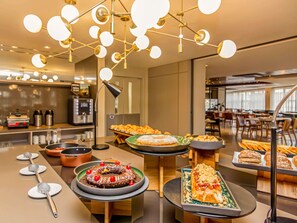 Un buffet proposant une variété de plats, agrémenté d’un luminaire moderne.