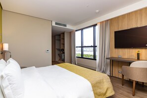 Een hotelkamer met een bed, een bureau, een stoel, een televisie en een raam met uitzicht.