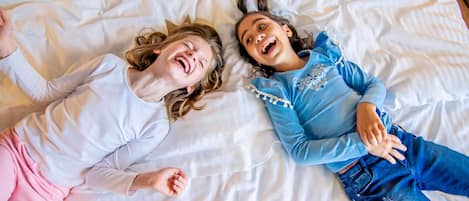Two people lying on a bed with white bedding.