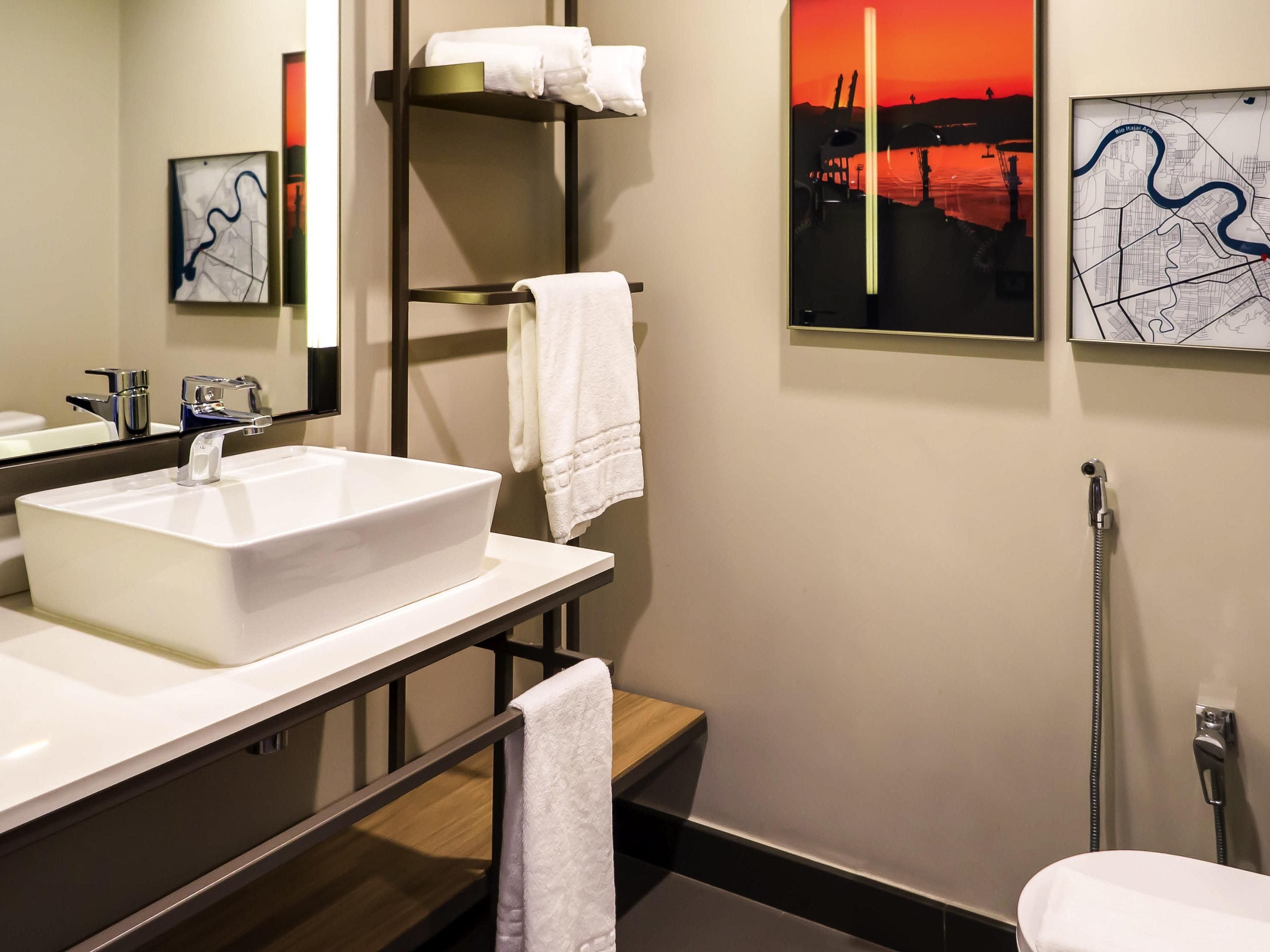 A modern bathroom with a white sink, a towel rack, and a shower.