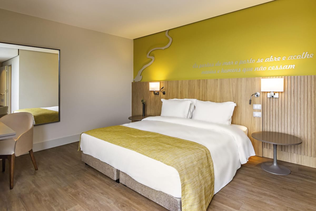 Ein Hotelzimmer mit Bett, Nachttisch, Stuhl und Spiegel.