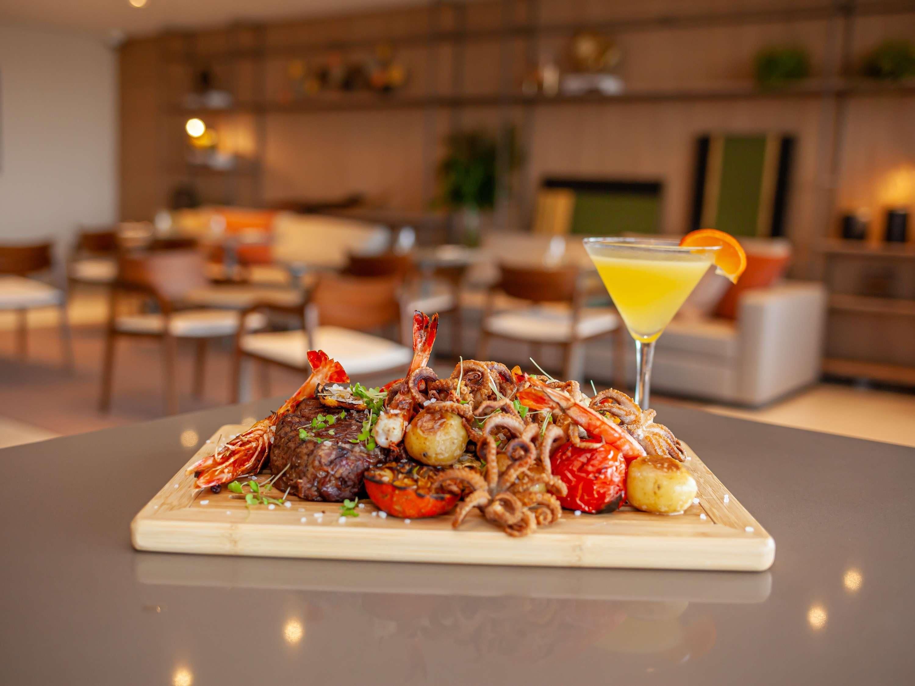 A dining table with a seafood platter, a martini glass, and a modern interior.