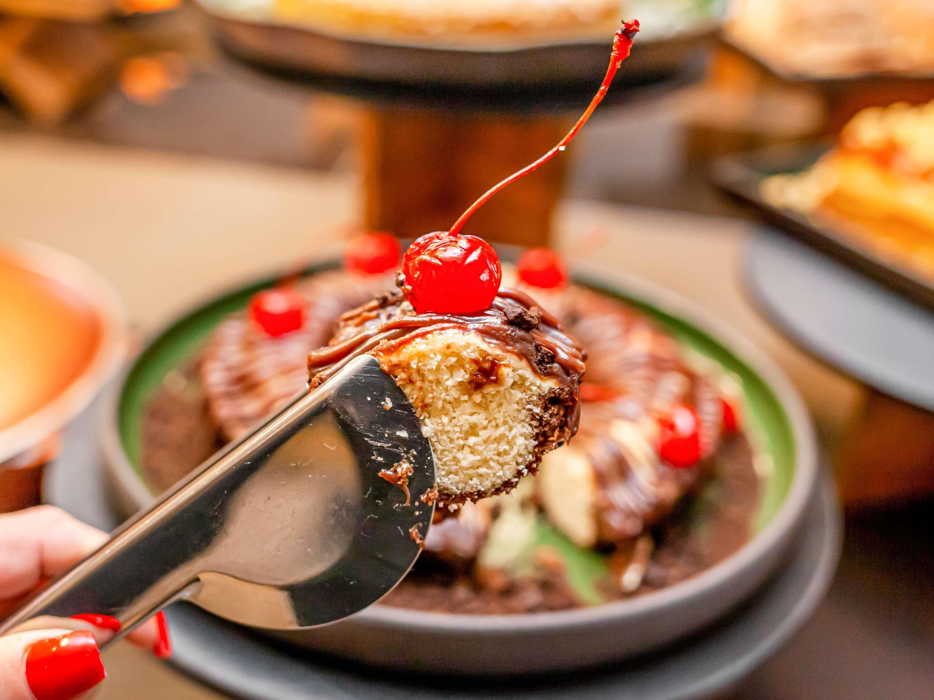 A dessert with a cherry on top, being served with a spoon.