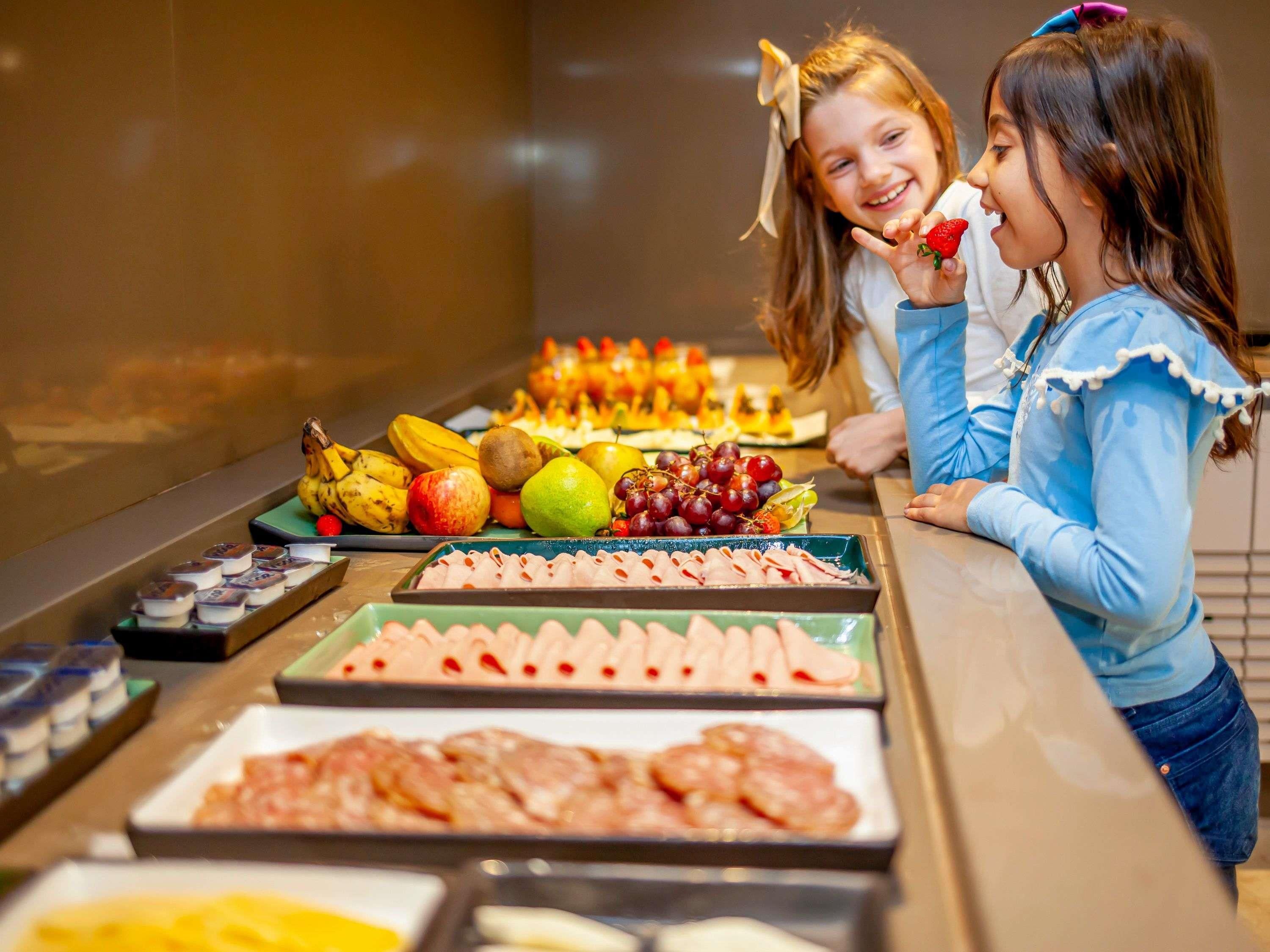 A buffet with various food items including fruits, meats, and cheeses.