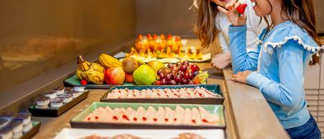 A buffet with various food items including fruits, meats, and cheeses.