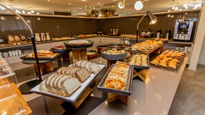 Un bufé con diversos alimentos, entre ellos pan, pasteles y ensaladas.