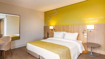 A hotel room with a bed, bedside table, chair, and a wall with a decorative element and text.
