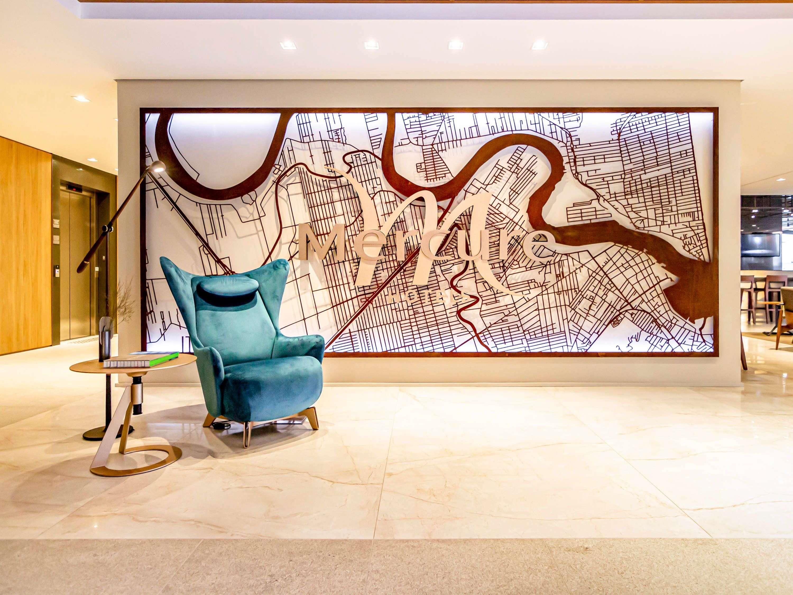 Un vestíbulo moderno con un mural grande de un mapa, un sillón azul y una pequeña mesa con un teclado.