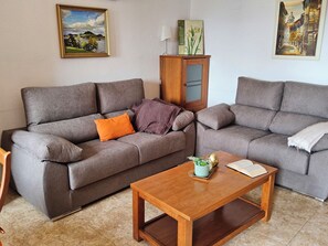 A living room with two grey sofas, a wooden coffee table, and a cabinet with artwork.