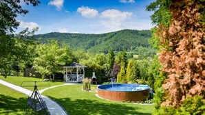 A garden with a gazebo, a swimming pool, and a clear view of a forested hill.