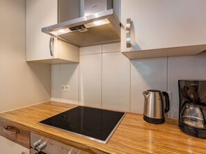 Een koelkast, een oven, een vaatwasser, kookgerei, borden en bestek