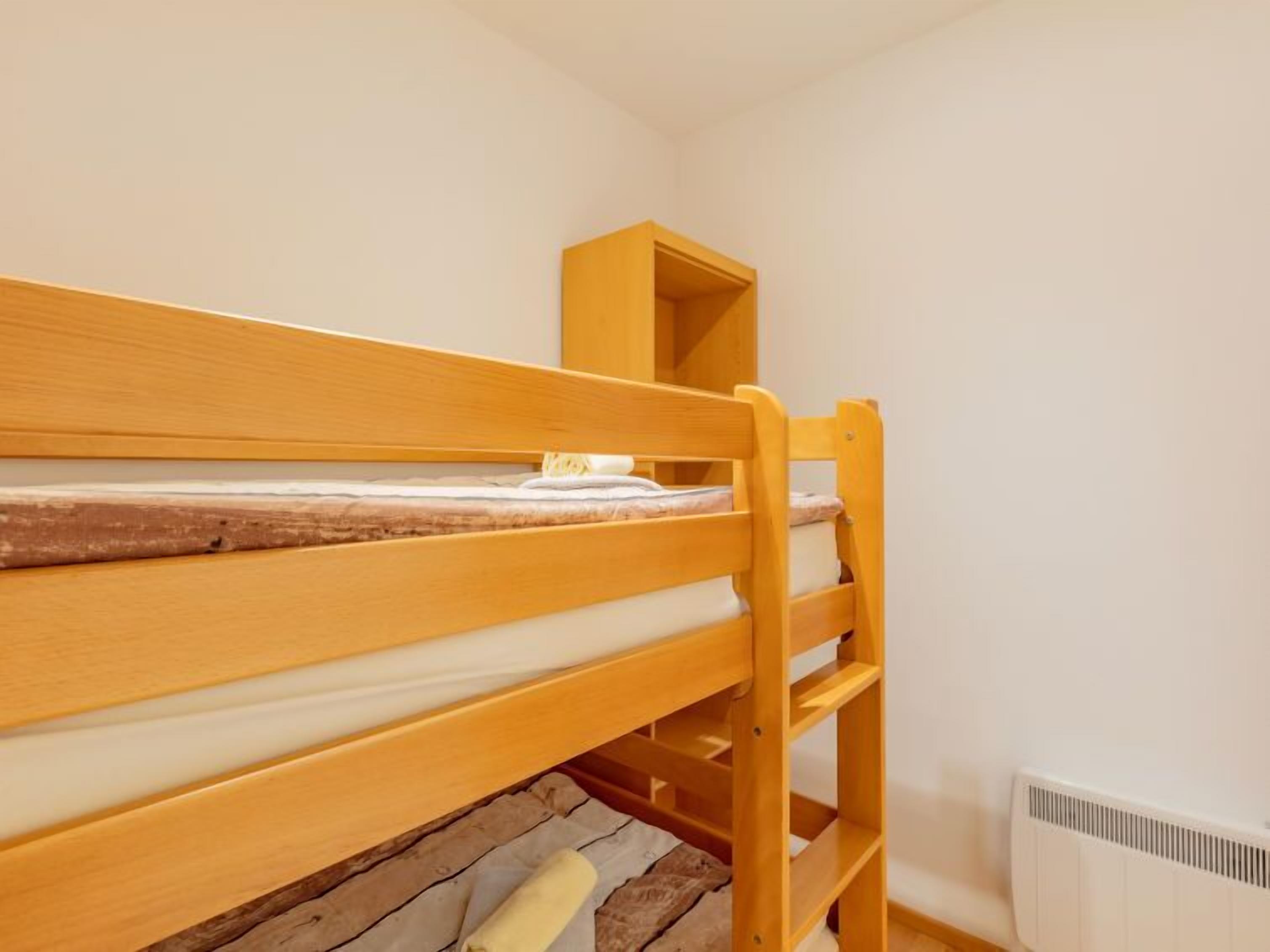 Una cama litera con estructura de madera y ropa de cama blanca.