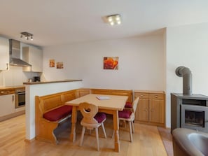 Une cuisine compacte dotée de meubles en bois, d’une cuisinière intégrée et d’un coin repas avec un banc et des chaises.