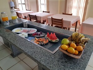 A breakfast buffet with various fruits, vegetables, and beverages.