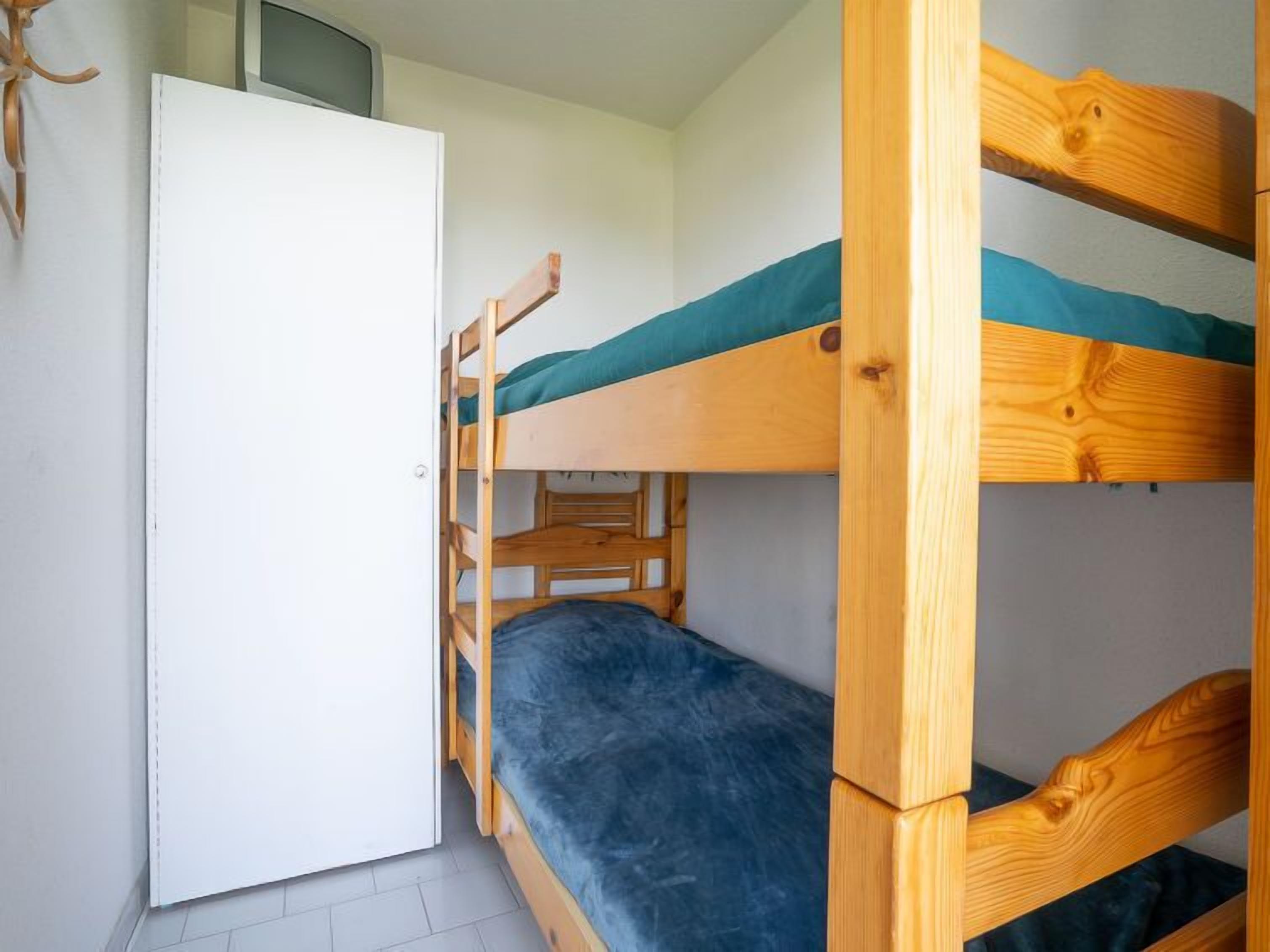 Habitación con literas, una puerta blanca y un ventanal pequeño.