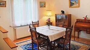 A dining area with a round table, chairs, a chandelier, a lamp, a cabinet, and a window with curtains. - 5, chemin de la Pralay by Interhome (Geneva)
