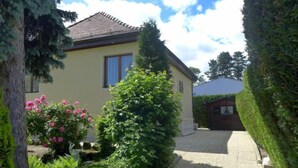 A house with a paved driveway leading to a garage, surrounded by well-maintained hedges and a variety of shrubs. - 5, chemin de la Pralay by Interhome (Geneva)