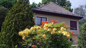 A house with a tiled roof, surrounded by lush greenery and flowering plants. - 5, chemin de la Pralay by Interhome (Geneva)