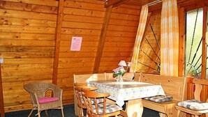 Ein gemütliches Interieur einer Holzhütte mit einem Esstisch, gedeckt für vier Personen, umgeben von Holzstühlen.