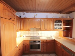 Een koelkast, een oven, een vaatwasser, kookgerei, borden en bestek