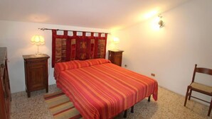 A bedroom with a bed, two nightstands, a chair, and a rug.