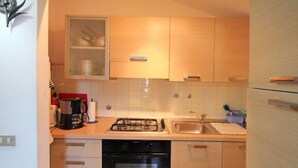 A compact kitchen with a gas stove, oven, and sink. There are wooden cabinets and a dishwasher.
