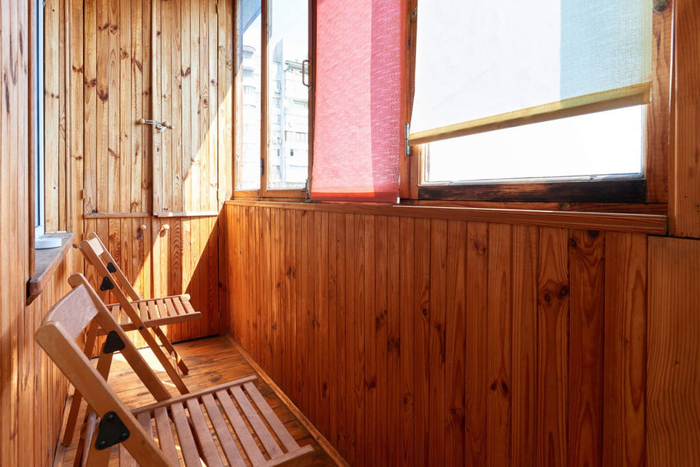 Ein Zimmer aus Holz mit Fenster, Holzbanken und einer Tür.