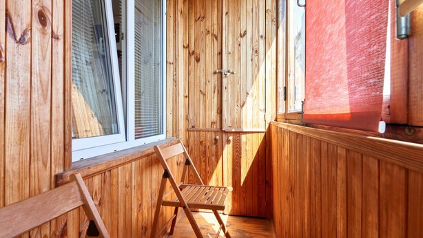 Ein Zimmer mit Holzwänden, einem Fenster, einer Bank und einer Tür.