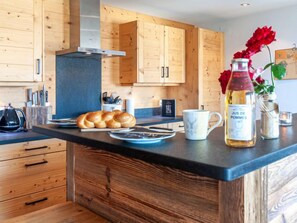 A modern kitchen with wooden cabinets, a black countertop, and a bottle of Jus de Pommes. - Montagnard 10 by Interhome (Nendaz)