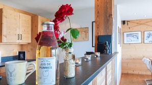 Un comptoir de cuisine avec une bouteille de jus de pomme, une tasse et un vase rempli de fleurs.