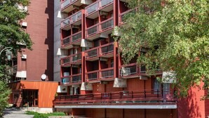 A multi-story building with balconies, a staircase, and a small outdoor seating area with flowers. - Lunik Orion by Interhome (Le Corbier)