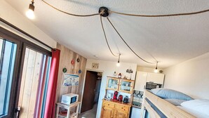 A compact room with a bunk bed, a small kitchenette, a wooden cabinet with glass doors, and a desk with a chair. - Apartment Ariane by Interhome (Le Corbier)