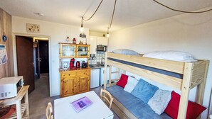 A compact room with a bunk bed, a kitchenette, a small dining table, and a white cabinet. - Apartment Ariane by Interhome (Le Corbier)