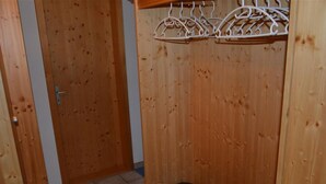 Une pièce en bois avec une porte, un banc et un étagère fixée au mur.