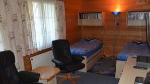Une petite pièce agréable, avec un lit, deux chaises, un bureau et une bibliothèque.