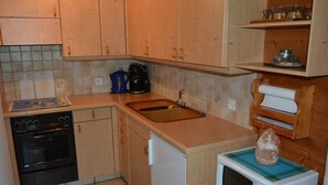 Une cuisine de taille réduite, dotée de meubles en bois, d  ’une cuisinière noire, d’un évier et d’un four à micro-ondes.