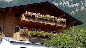 A wooden chalet with balconies adorned with flowers, set against a mountainous backdrop. - Oltschiblick by Interhome (Brienzwiler)