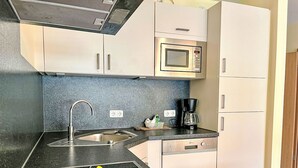 A modern kitchen with a black countertop, stainless steel sink, microwave, and coffee maker. - Zum Trichter by Interhome (Palzem)
