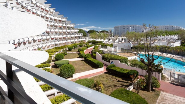 Un complexe hôtelier doté d’une piscine, de jardins bien entretenus et d’un grand bâtiment blanc agrémenté de balcons.