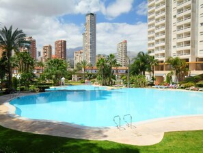 A large outdoor swimming pool surrounded by palm trees and a cityscape with tall buildings in the background. - Los Gemelos by Interhome (Benidorm)