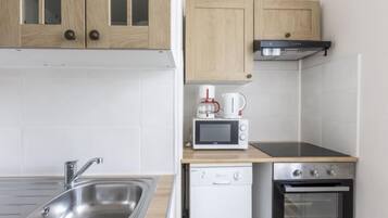 Een koelkast, een oven, een vaatwasser, kookgerei, borden en bestek