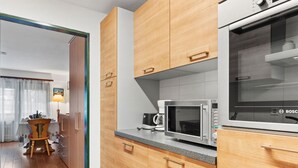 A modern kitchen with wooden cabinets, a Bosch microwave, and a coffee maker. - Residence A by Interhome (Zermatt)